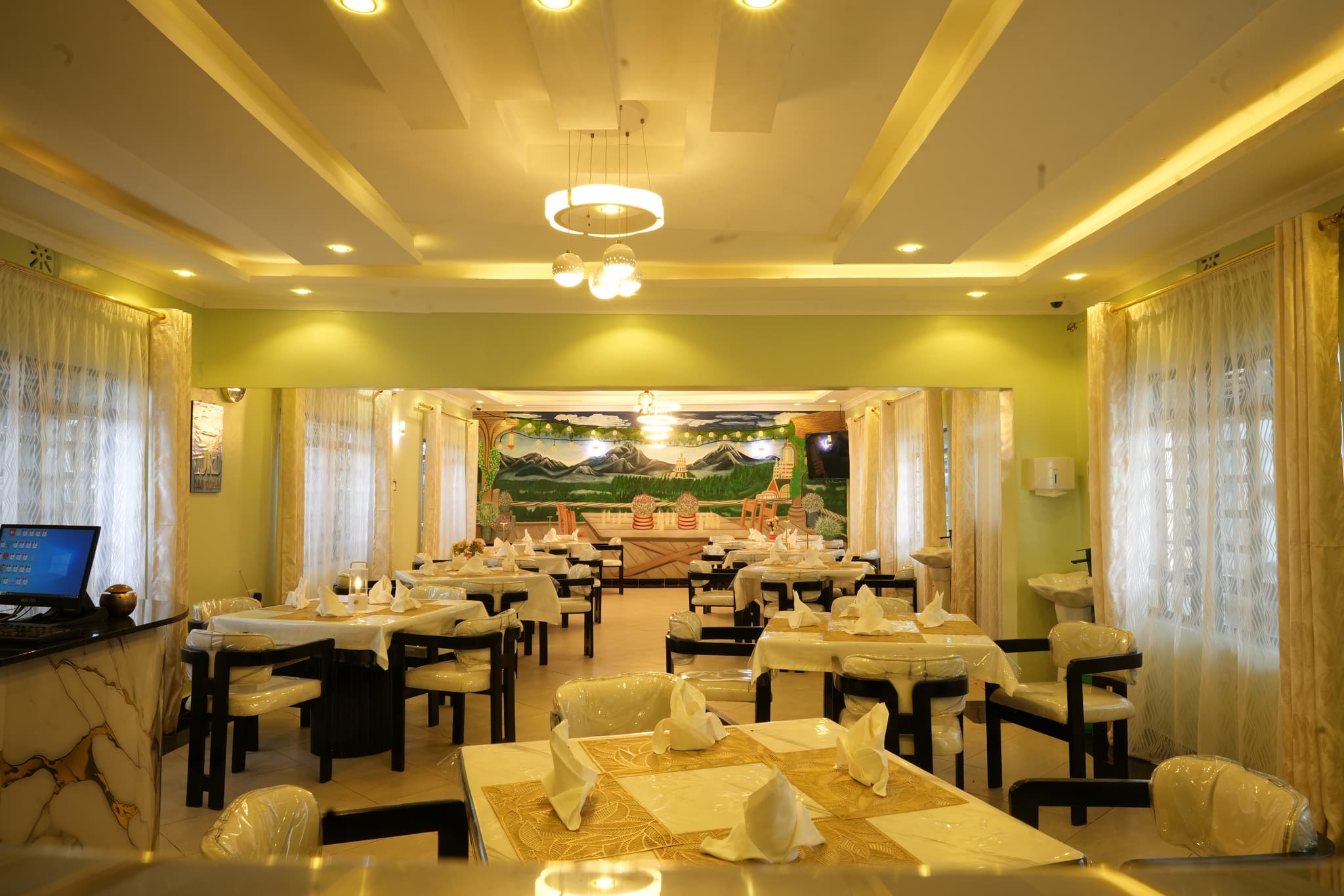 Intimate restaurant interior with timber tables and woven pendant lights overlooking green hills